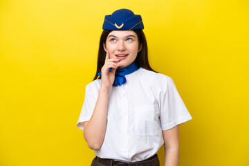 Airplane stewardess Russian woman isolated on yellow background thinking an idea while looking up