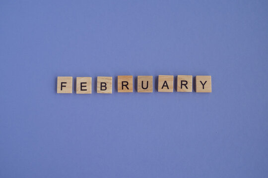The second month of the year is FEBRUARY - from letters on wooden blocks in natural color, in high resolution. Very Peri Color of the Year 2022 background, copy space. Flat lay, step by step, step2.