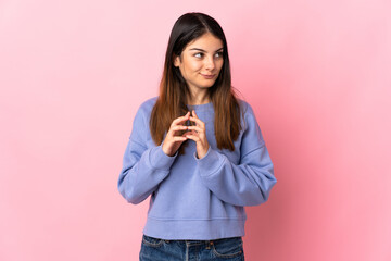 Young caucasian woman isolated on pink background scheming something