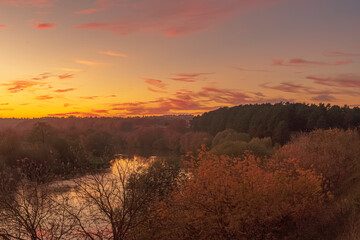Beautiful autumn after sunset scene over the river with gradient orange to pink blue sky