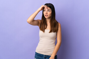 Young caucasian woman isolated on purple background doing surprise gesture while looking front