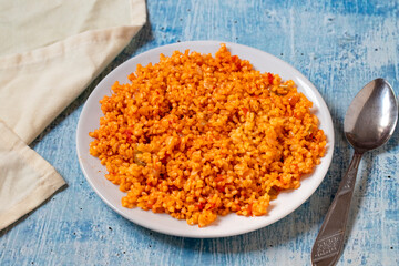 Bulgur pilaf on a blue background. Close-up of Turkish food Bulgur Pilav in a ceramic plate