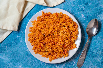 Bulgur pilaf on a blue background. Close-up of Turkish food Bulgur Pilav in a ceramic plate. Top view