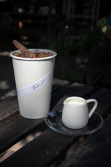 a cup of milk placed beside a paper coffee cup with a sticker Thank you attach to its