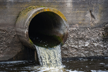 Dirty water flows from the pipe into the river, environmental pollution. Sewerage, treatment facilities - obrazy, fototapety, plakaty