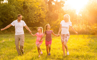 Fototapeta na wymiar Happy family walking in field and looking at sunset