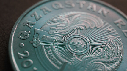 Fototapeta na wymiar Translation: Kazakhstan. Kazakh 50 tenge coin with the country emblem and focus on shanyrak. Close-up. Green tinted background or wallpaper for Kazakh economy or state. Macro