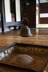 大きな日本家屋の中にある古びた炉端の上では自在鉤が薬罐を吊っている