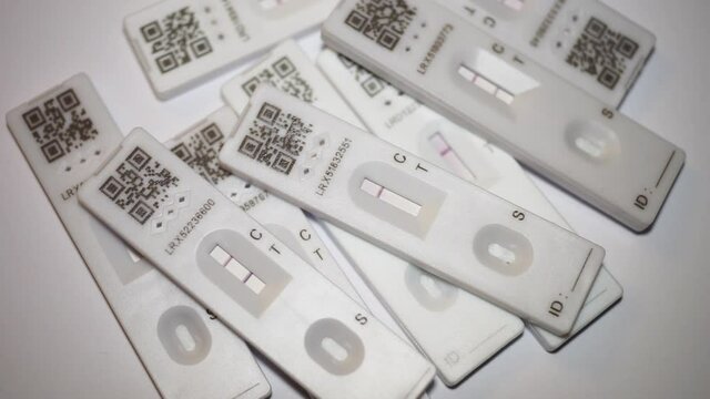 London, England, January 12th 2022: Rapid Covid-19 home lateral flow antigen used test cassettes, piling up. Placing a negative cassette in the middle of the stack. Concept for regular home testing.