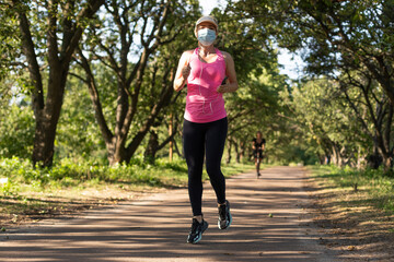 Obraz premium Pandemic coronavirus COVID-19 A woman in a meadow in a sports outfit wearing a protective mask in case of the spread of SARS-CoV-2 disease virus. Girl with a protective mask on her face.