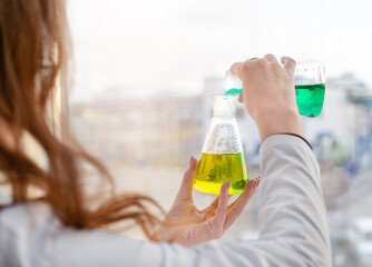 A girl laboratory assistant mixes reagents in a chemical laboratory