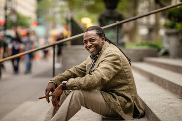 Fashionable portrait of middle aged elegant afro American man wearing brown suit smoking cigar....