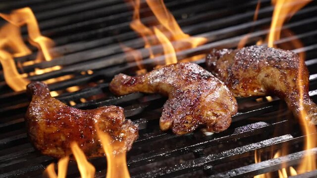 Chicken thighs grilled on hot barbecue charcoal flaming grill. Juicy chicken meat roasted on bbq grill. slow motion