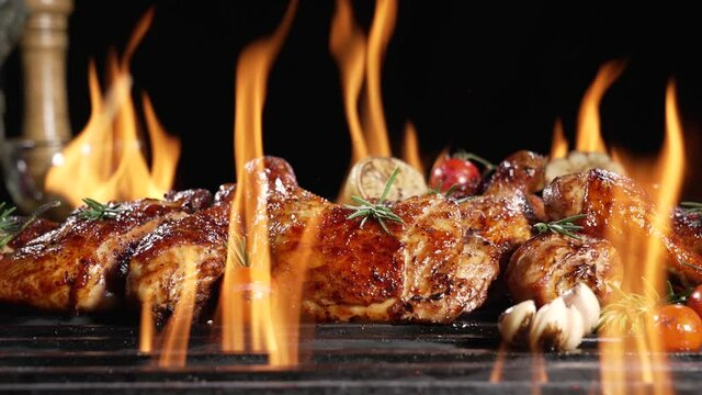 Chicken drumsticks and thighs grilled on hot barbecue charcoal flaming grill. Juicy chicken meat roasted on bbq grill. slow motion