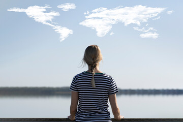 Frau blickt auf Horizont mit Wolken in Form der Welt