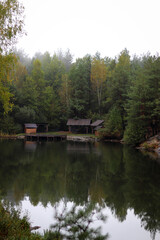 Obraz premium Wood house beside the lake in pine forest. Summer wooden lake house inside forest .