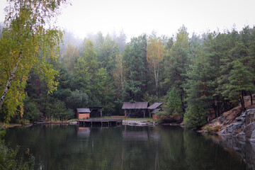 Wood house beside the lake in pine forest. Summer wooden lake house inside forest .