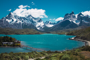 Fototapeta na wymiar Lake with a bridge to a house with snowy mountains in the background in the Torres del Paine area of ​​Chilean Patagonia