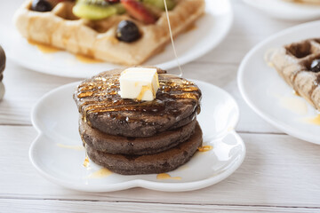 Pancake with butter and honey maple syrup set on white cafe table.