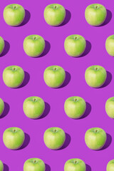 Pattern made of green apples on purple background. Minimal fruit concept. Apples pattern on ultra violet background. Organic and healthy food.