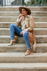 Thoughtful woman thinking about something while sitting on the stairs in the street.