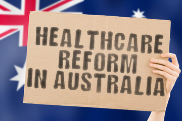 The phrase " Healthcare reform in Australia " on a banner in men's hand with blurred Australian flag on the background. Nation. Crisis. Problem. Medical help. Reformation. Clinical