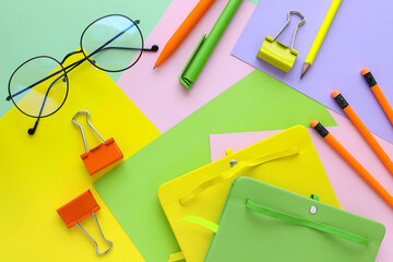Colorful notebooks and office supplies on colorful background