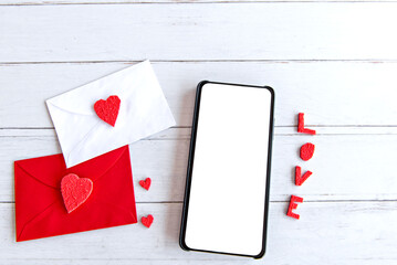Valentine's day concept, love letter and cellphone with white screen on wooden table.