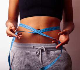 woman measuring waist with tape on knot, african tan isolated