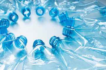 Blue plastic bottles lie in a circle with necks in the center on a white background