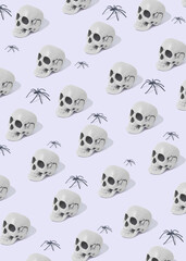 White skull and spiders on grey pastel background. Halloween minimal concept. Halloween mood. New Year’s greeting card. Pattern with skulls and spiders. Flat lay. Scary wallpaper. Trick or treat.