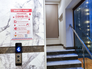 Coronavirus COVID 19 SARS-COVID guidelines and warning on the side of a lift staircase as hotels offices open up post the pandemic with the omicron variant spreading