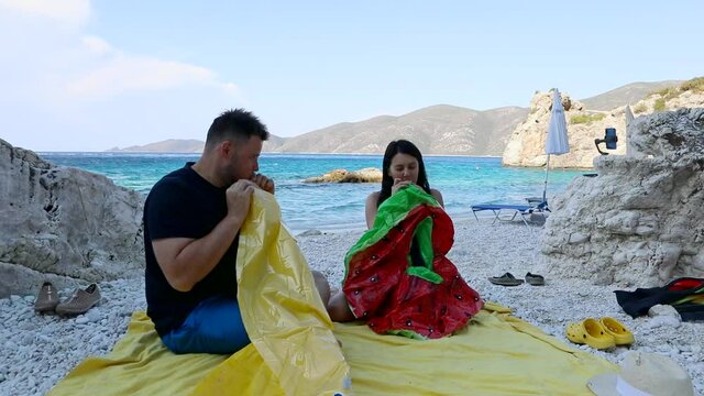 couple having fun inflate inflatable mattress at sea beach