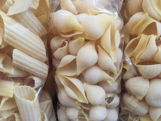 Different shapes of raw pasta in a transparent plastic bag. 