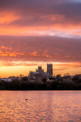 Cathedral of Ely with beautiful sunset colours in the sky infront of a lake