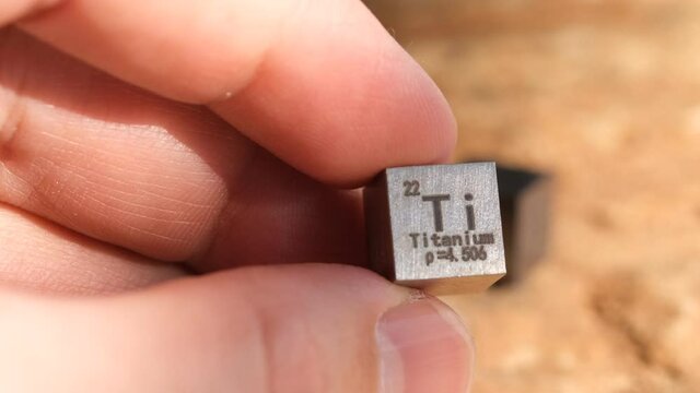 cube of titanium ore in a man's hand.	

