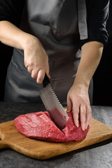 The cook cuts a piece of meat close-up.