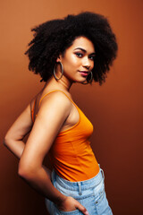Naklejka premium pretty young african american woman with curly hair posing cheerful gesturing on brown background, lifestyle people concept