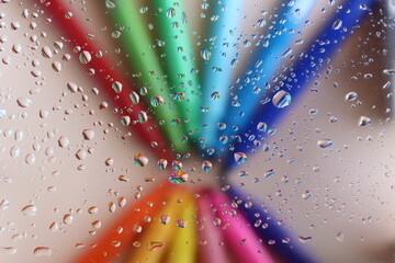 Wet glass and behind a set of markers of various colors