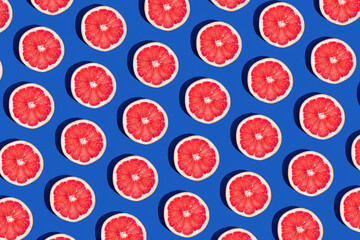 Minimal fruit pattern with grapefruit on blue  background. Creative  summer mood. Healty concept. Organic fruit. Flat lay. Trendy social mockup or wallpaper. - obrazy, fototapety, plakaty