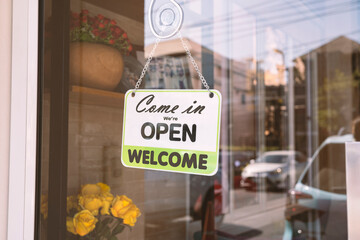 Open sign broad through the glass of door in cafe