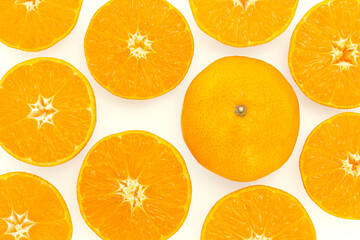 Whole tangerine among juicy orange slices of tangerine on light background. Bright creative background. Top view