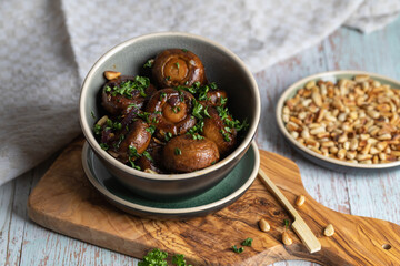 Plate of fried mushrooms with dill, garlic, pine nuts and parsley.