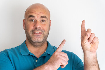 Portrait of middle-aged Caucasian man pointing up with his index fingers, on white background.