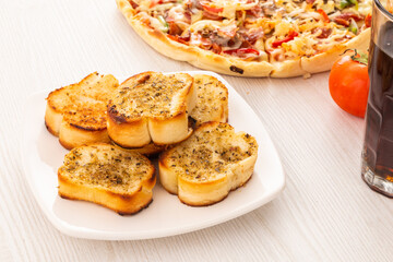 plate with garlic bread in the background a pizza and glass with soda, food and drink served on the restaurant table, texture details, lunch