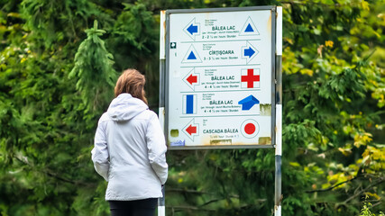A woman looking at a guide sign at Balea resort in Romania