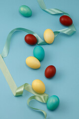 Colorful Easter eggs with green ribbon on blue background