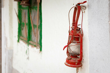 Red, vintage lantern hanging on the wall.