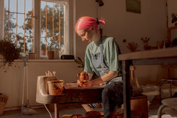 Young female master working with clay in pottery room