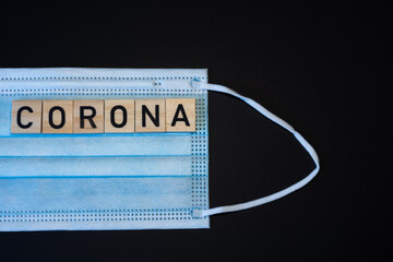 The word corona on wood with face mask on black background